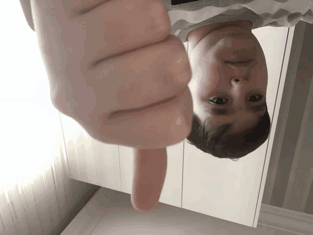 a person giving a thumbs down sign with their face upside down
