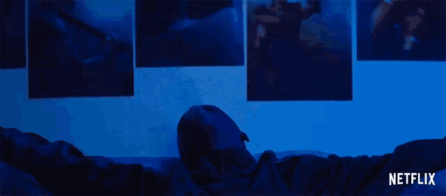 a man is laying on a bed with his arms outstretched in front of a wall with netflix written on the bottom