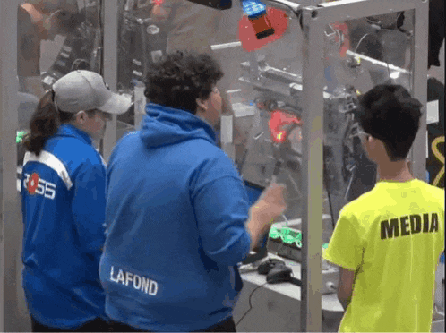 a boy wearing a yellow shirt that says media stands in front of a machine