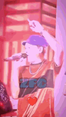 a man in a purple hat is singing into a microphone while wearing a shirt that says zfc