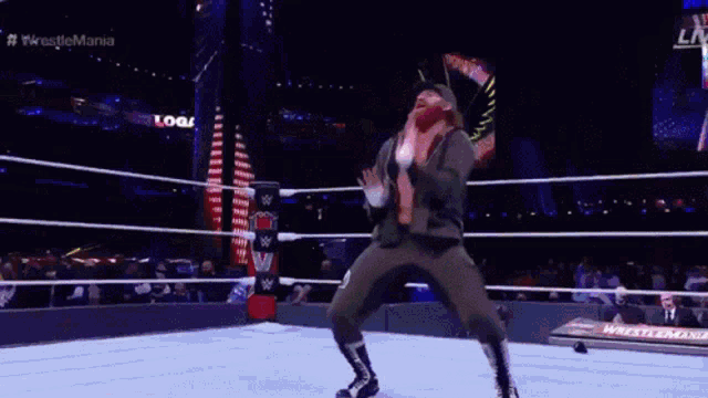 a wrestler is jumping in the air in a wrestling ring with the words wrestlemania in the background