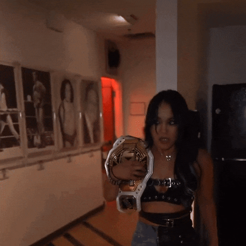 a woman is holding a wrestling championship belt with the letter t on it