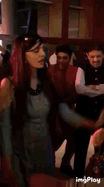 a woman in a blue dress is dancing in front of a group of people ..