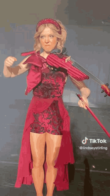 a woman in a red dress is playing a violin with a tiktok watermark