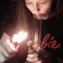 a girl wearing a black shirt that says barbie is smoking a bong