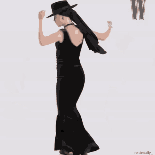 a woman wearing a black dress and a black hat with the letter w in the corner