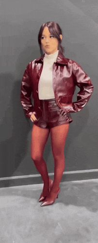 a woman wearing red tights and shorts is standing in front of a wall .