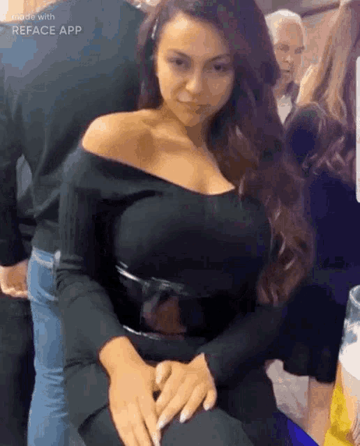 a woman in a black off the shoulder dress is sitting in a crowd of people .