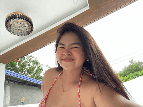 a woman in a bikini is smiling in front of a ceiling light