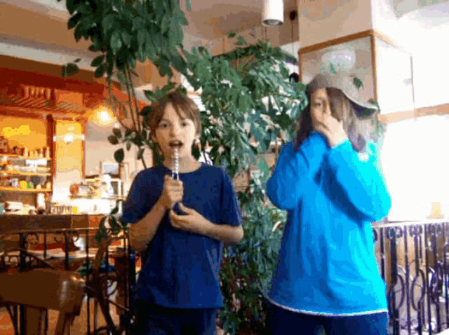 a boy in a blue shirt is blowing bubbles while standing next to a girl in a blue shirt