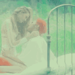 a man and a woman are kissing on a bed with a green background