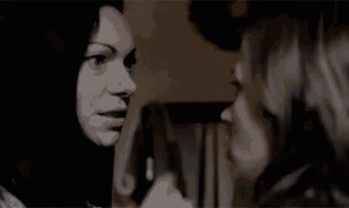 a woman is pointing at another woman 's face while they are looking at each other .