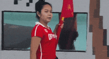 a woman wearing a red shirt with the letter a on it is holding a red flag