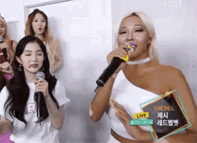 a woman is singing into a microphone in front of a group of girls .