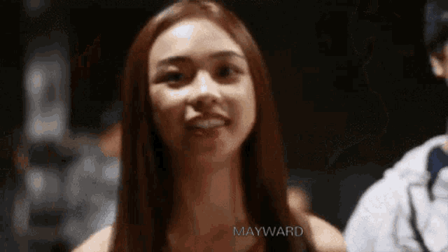 a woman with long hair is smiling and looking at the camera in a blurry photo .