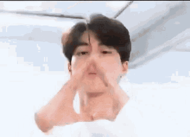 a young man in a white shirt is making a heart shape with his hands .