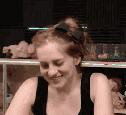 a woman wearing a black tank top with a bow in her hair