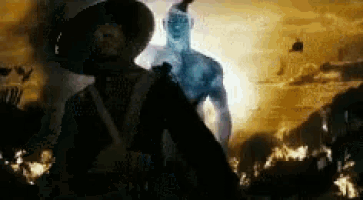 a man in a cowboy hat is standing in front of a giant man .