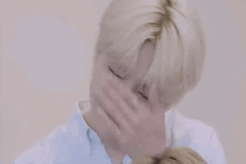 a man is covering his face with his hands while wearing a ring on his finger .