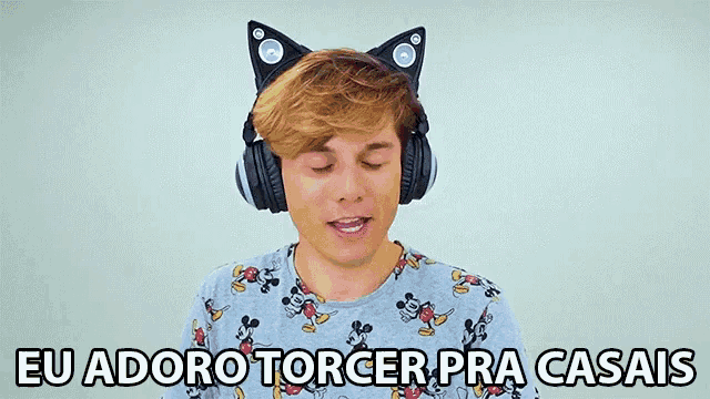 a young man wearing cat ears headphones says " eu adoro torcer pra casais "