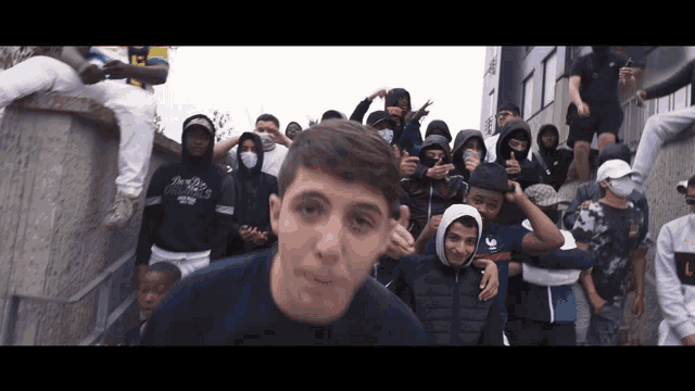 a boy wearing a sweatshirt that says ' new york ' on it stands in front of a crowd of people