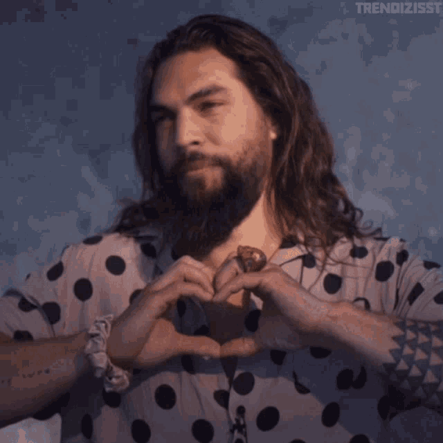 a man with long hair and a beard wearing a polka dot shirt with the word trendizsst on the bottom