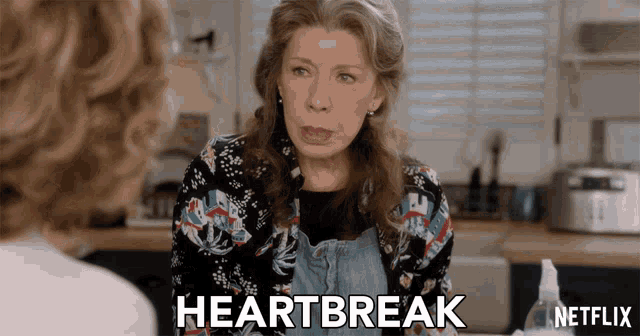 a woman is talking to another woman and the word heartbreak is visible