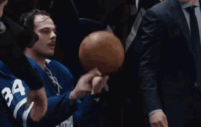 a man in a toronto maple leafs jersey is holding a basketball