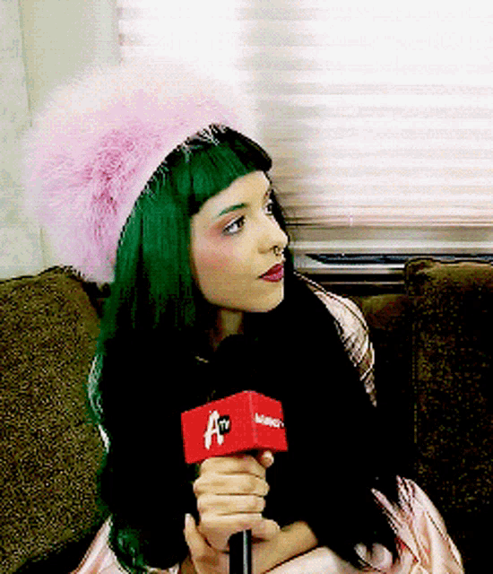 a woman with green hair is holding a red microphone that says a tv