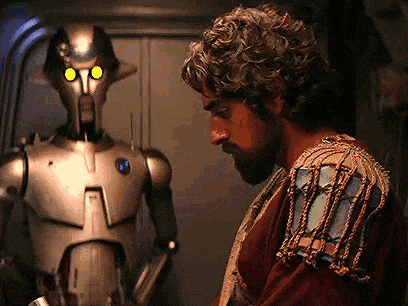 a man with curly hair is standing next to a robot with yellow eyes