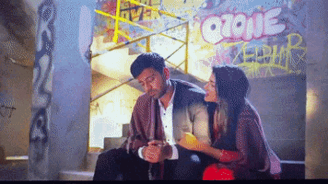 a man and a woman are sitting in front of a graffiti wall that says " gone "