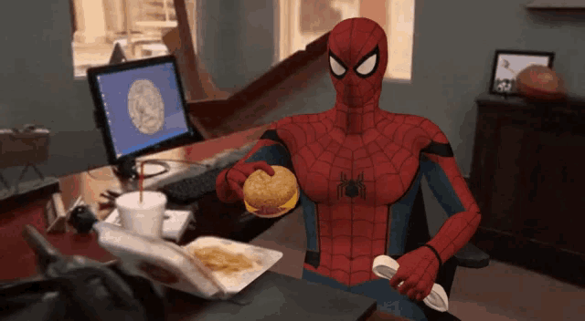 a cartoon of spider-man eating a hamburger in front of a computer