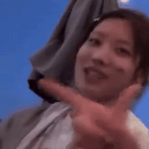 a close up of a woman making a peace sign with her hands .