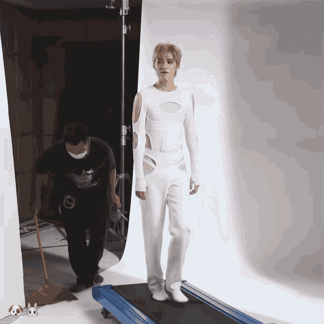 a man wearing a mask is standing next to a treadmill