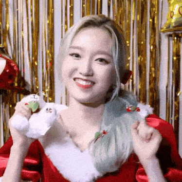 a woman wearing a santa claus costume is smiling and holding a stuffed animal