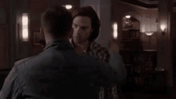 a couple of men are hugging each other in a living room .