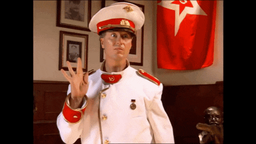 a man in a military uniform with a red star on his hat is standing in front of a red flag