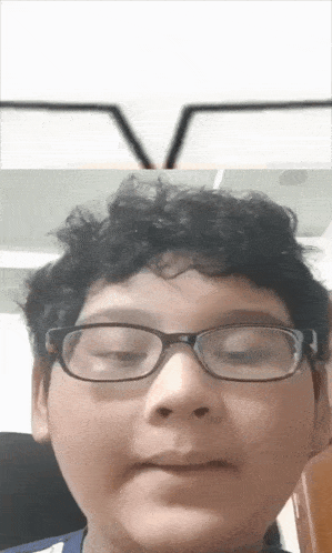 a boy wearing glasses looks at the camera