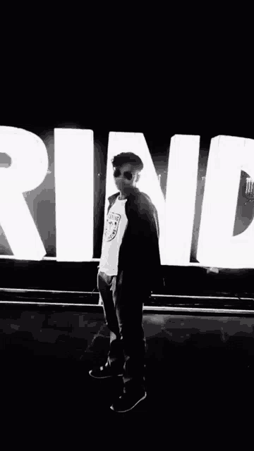 a man wearing sunglasses is standing in front of a large sign that says ring .