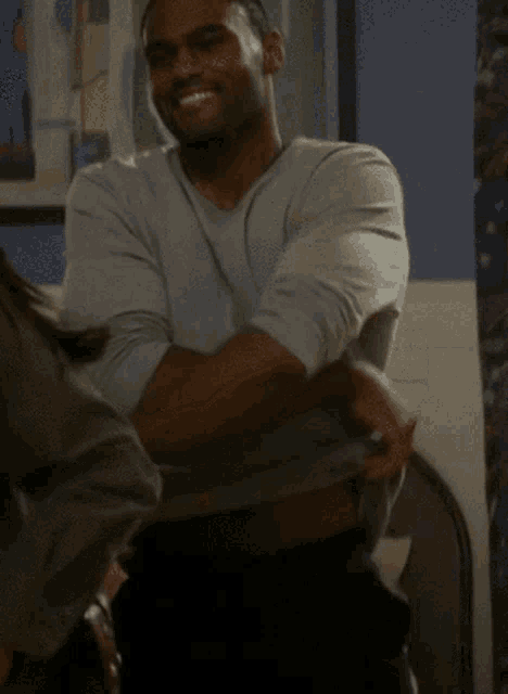 a man in a grey shirt is smiling while a woman holds his shirt