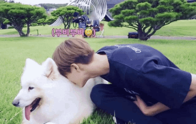 a man in a black t-shirt is kneeling down to pet a white dog