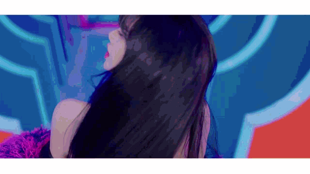 a woman with long black hair is standing in front of a colorful background .