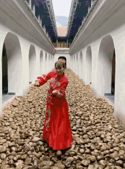 a woman in a red dress is standing in a hallway of rocks