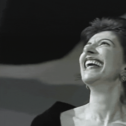 a woman is laughing with her eyes closed