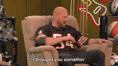 a bald man in a bears jersey is sitting in a chair and says " i brought you somethin "
