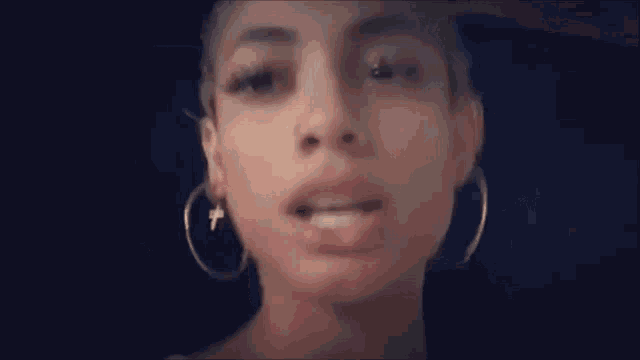 a close up of a woman wearing hoop earrings and a cross .