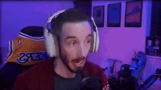 a man wearing headphones is sitting in front of a microphone in a room with purple lights .