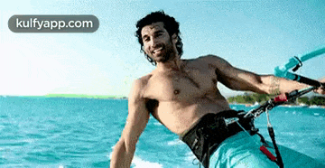a shirtless man is riding a jet ski in the ocean