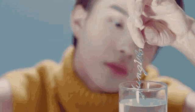 a close up of a person 's face with a glass of water in front of him .