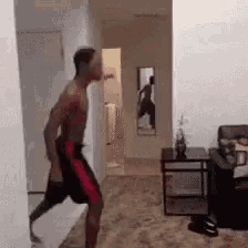 a shirtless man is walking through a living room .